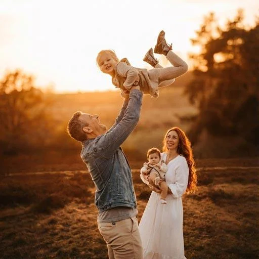 Családi Fotózás Budapesten, A Velencei-Tónál És Pest Megyében 1 Apuka A Levegőbe Emeli Kislányát Egy Vidám Családi Fotózáson Naplementében, Háttérben Az Édesanya A Kisbabával.